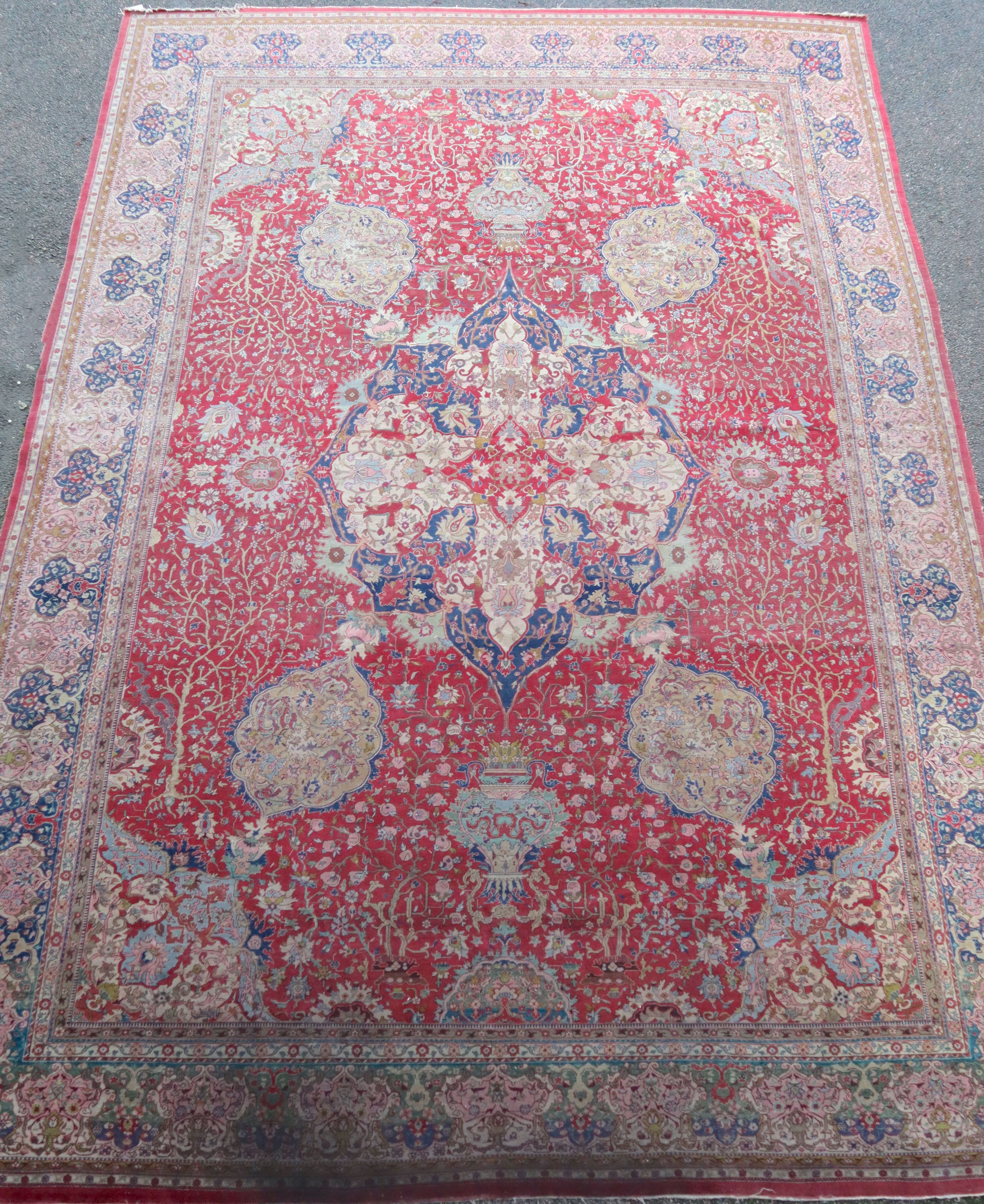 A Kirman carpet, the claret field with overall flowering shrub and palmette design centred by an indigo hooked medallion.